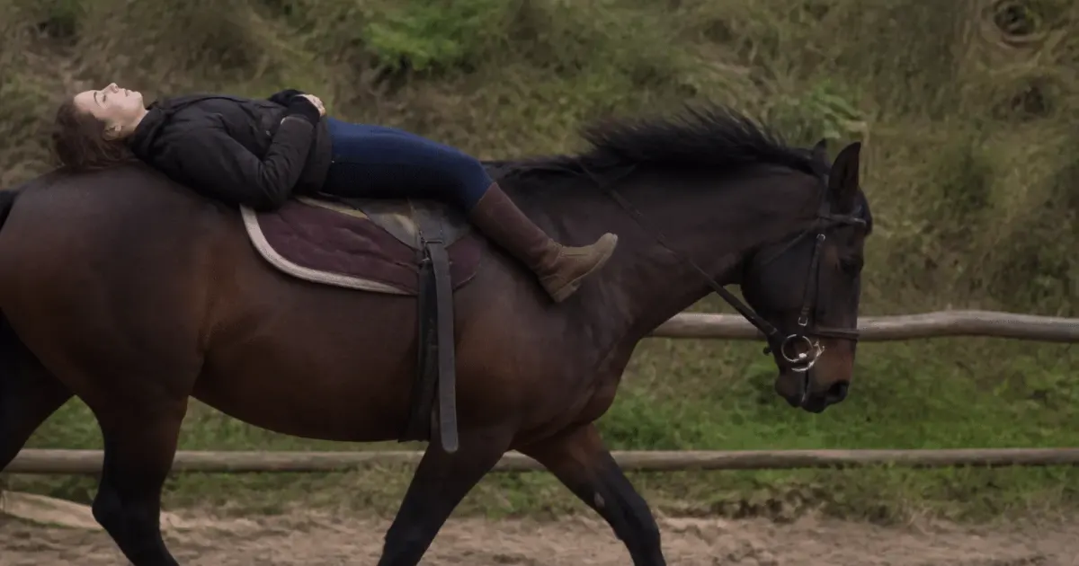 Personne allongee sur le dos d'un cheval en mouvement